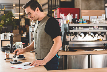 Happy man preparing appetizing coffee in cafe
