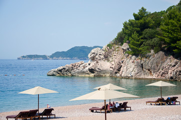 Fototapeta na wymiar Luxury sand beach with wooden chaise-longue chairs and umbrellas. The royal beach in Montenegro.