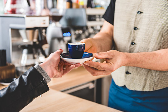 Male hand giving cup of delicious coffee to client