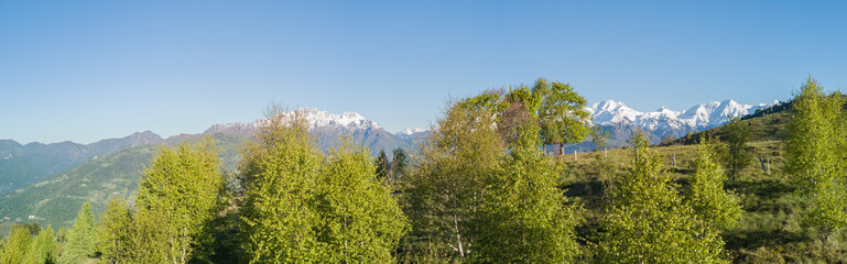 Drone aerial view to the Orobie Alps in a clear and blue day. Fresh snow on the top of mountain in spring. Panorama at Farno Mountain, Bergamo, Italy. 