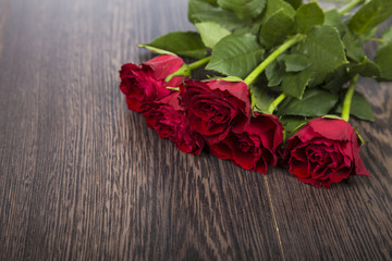 Red roses on a dark wooden background.