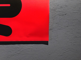 Minimalist delicious 04
Bright red poster with black curvy design detail over a grey plastered background wall.