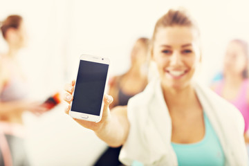 Portrait of beautiful mature woman with smartphone smiling in health club