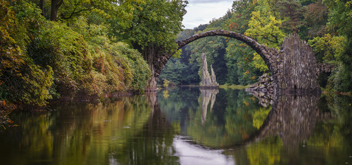 Fototapeta na wymiar Arch Bridge in Kromlau, Saxony, Germany. Colorful autumn in Germany. Rakotz bridge in Kromlau