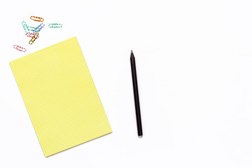 yellow Notepad, a pencil and a paper clip. Minimal business concept of working place in the office