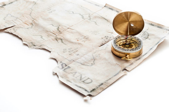 Close up to gold nautical compass on old vintage map with fake island of Pirates treasure