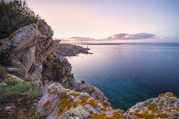 Seascape of the Italian coast at sunset with a lighthouse in the background. Porto Cervo - Emerald...