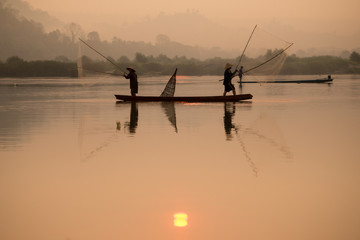 Fisherman catching fish at dawn in Thailand