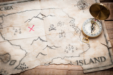 Abstract map of treasure island with gold compass on wood table