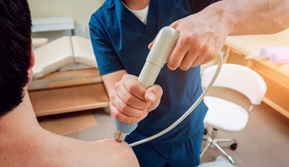 Shock wave therapy. The magnetic field, rehabilitation. Physiotherapist doctor performs surgery on a patient's shoulder