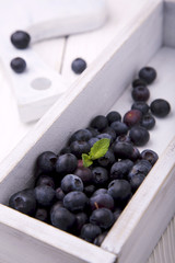 Blueberries in white wooden box on white wooden surface
