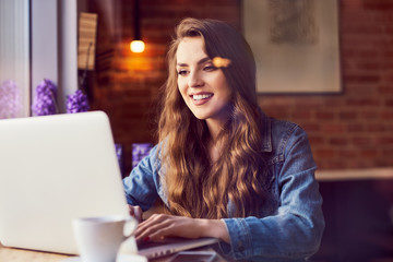 Beautiful young woman using her laptop at cafe