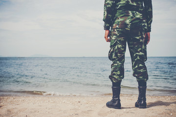 The soldiers stood at the beach and looked out to sea.