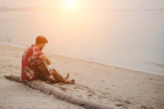 Young Man Playing The Guitar On The Beach.