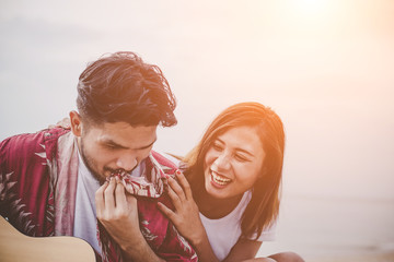 Young couples playing guitar and singing on the beach.
