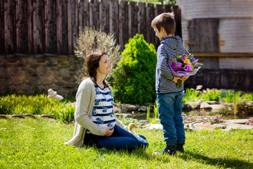 Young pregnant woman, receiving bouquet of colorful flowers from her child for Mothers Day