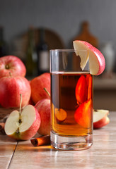 Glass of apple juice and ripe pink apples on a kitchen table