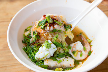 A Big bowl of spicy seafood noodles soup (Tom Yam)with squid, shrimps Asian green mussels and boiled egg - Traditional Thai food
