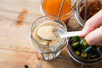 Thai style Seasoning, fish sauce, sugar, vinegar and chilli powder in glasses and aluminium cover on wooden brown table, street food restaurant