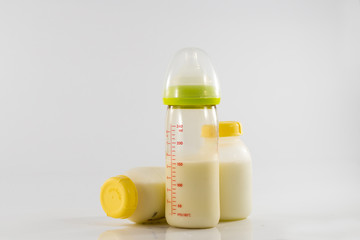 Baby bottle with milk and a measuring scale on the background of a lot of full bottles of breast milk. Mother's milk - the most healthy food for newborn