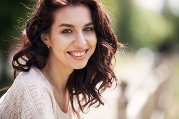 Young smiling woman outdoors portrait. Soft sunny colors.