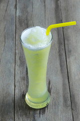 Green Apple juice in glass on wooden table floor.