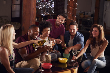 Young adult friends drinking and eating snacks at home