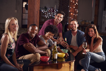 Young adult friends having a party at home look to camera