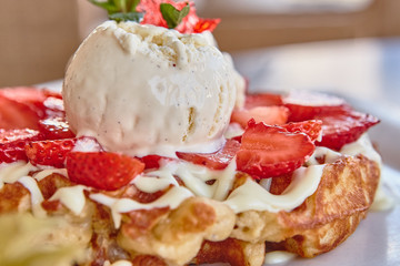 waffles with white chocolate sauce, ice cream and strawberries