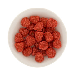 Top view of raspberry shaped candy in a small bowl isolated on a white background.