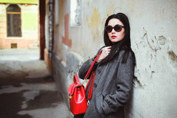 Obraz premium Long hair girl near old wall with red backpack