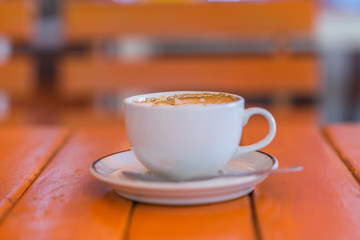 A cup of coffee on an orange table and background.