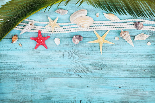Palm leaves, rope, seashell and starfish on blue wooden table top view in flat lay style. Summer holidays, travel and vacation background.