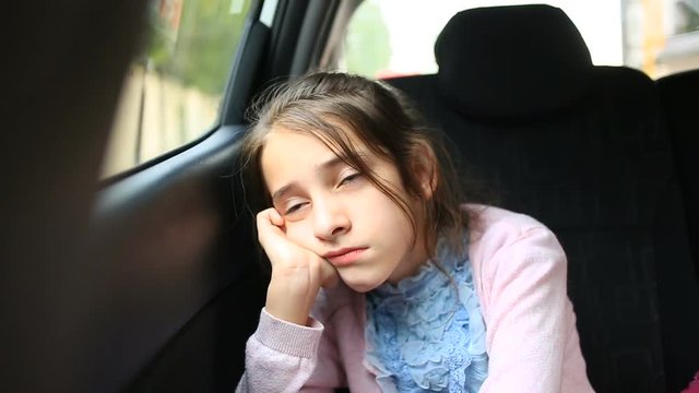 Little girl, bored in the car - looking out the window through the window - street reflection