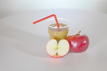 Apple juice is standing on the kitchen table. There is an apple cut in halves on the table, too. - Powered by Adobe
