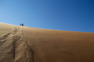 Fototapeta na wymiar People Climbing Down Big Daddy Dune into Sossusvlei Salt Pan, Desert Landscape, Namibia