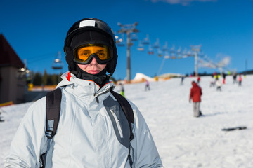 A young man in ski suit, with helmet and ski goggles standing in a ski resort