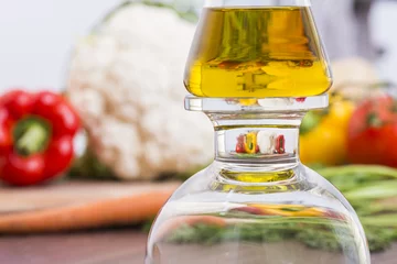Fototapeten Olivenölflasche mit Gemüsevergrößerung im Hintergrund © Sebastian