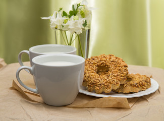 white Cup with milk, cookies and a bouquet