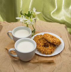 white Cup with milk, cookies and a bouquet