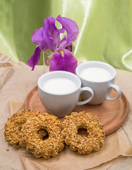 white Cup with milk, cookies and a bouquet