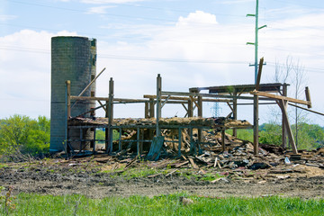 old barn with silo being dismantled on farmland