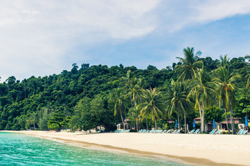 Obraz premium tropical beach with Chairs and umbrella, palm tree and blue sky.