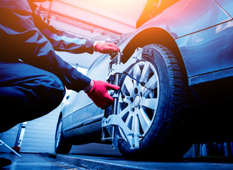 Car mechanic installing sensor during suspension adjustment.