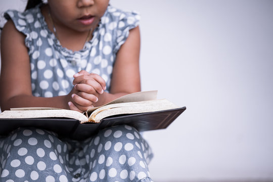 Little girl hands folded in prayer on a Holy Bible on white background  for faith concept in vintage color tone