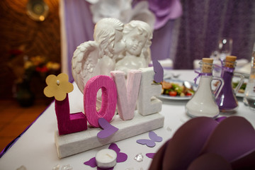 Inscription "Love" and kissing cupids on wedding table
