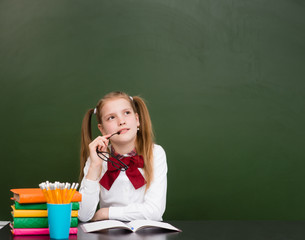 Dreaming teen girl near empty school green chalkboard