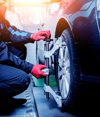Car mechanic installing sensor during suspension adjustment.