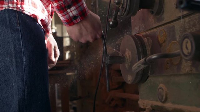 Close up footage of male worker in plaid red shirt operating woodworking machine in slowmotion