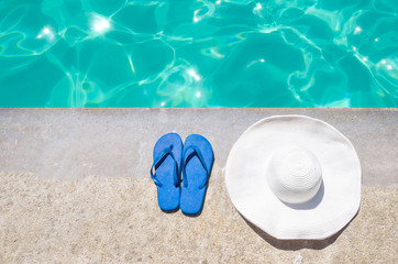 Fototapeta na wymiar Summer hat and flip flops near the pool